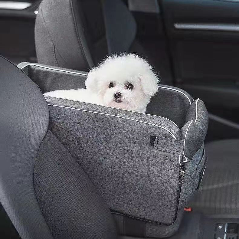 A small white dog sitting in the Road Nest car seat fitted to a rear seat