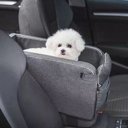A small white dog sitting in the Road Nest car seat fitted to a rear seat