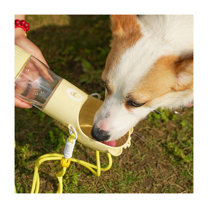 A dog drinking from the Rover Bottle held out on a grassy path
