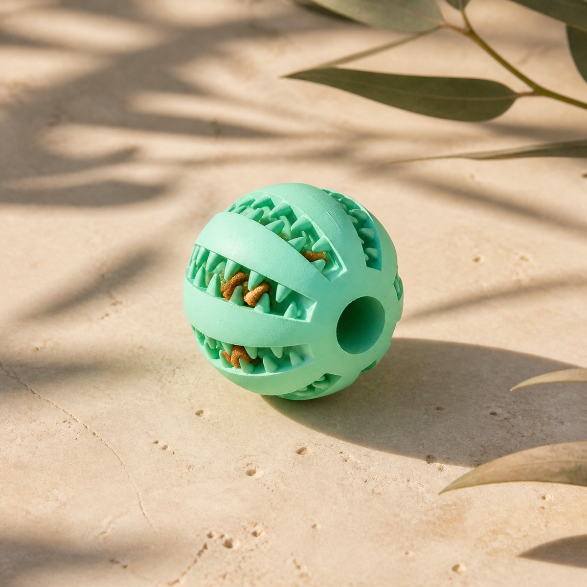 Mint textured enrichment ball with treats on pale limestone